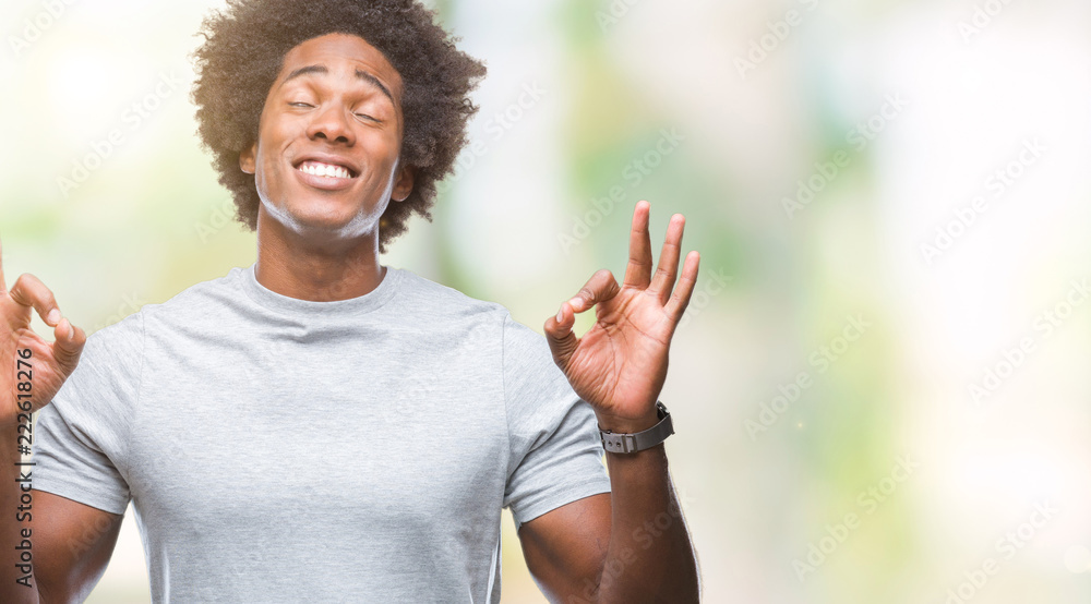 Afro american man over isolated background relax and smiling with eyes closed doing meditation gesture with fingers. Yoga concept. Afro american man over isolated background relax and smiling with eyes closed doing meditation gesture with fingers. Yoga concept.