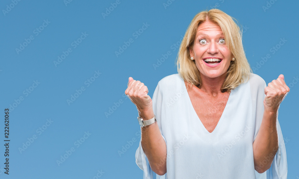 Fototapeta premium Middle age blonde business woman over isolated background celebrating surprised and amazed for success with arms raised and open eyes. Winner concept.