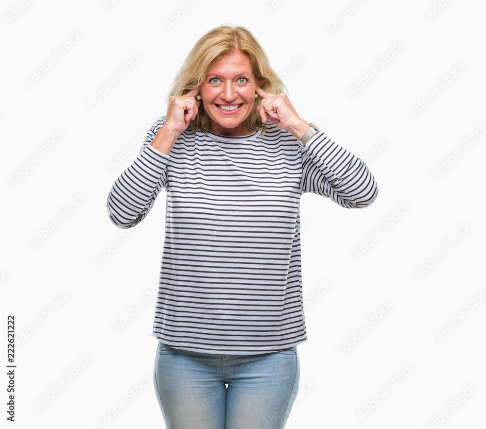 Middle age blonde woman over isolated background covering ears with fingers with annoyed expression for the noise of loud music. Deaf concept. Middle age blonde woman over isolated background covering ears with fingers with annoyed expression for the noise of loud music. Deaf concept.