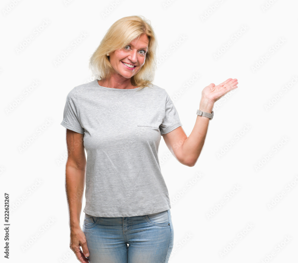 Middle age blonde woman over isolated background smiling cheerful presenting and pointing with palm of hand looking at the camera. Middle age blonde woman over isolated background smiling cheerful presenting and pointing with palm of hand looking at the camera.