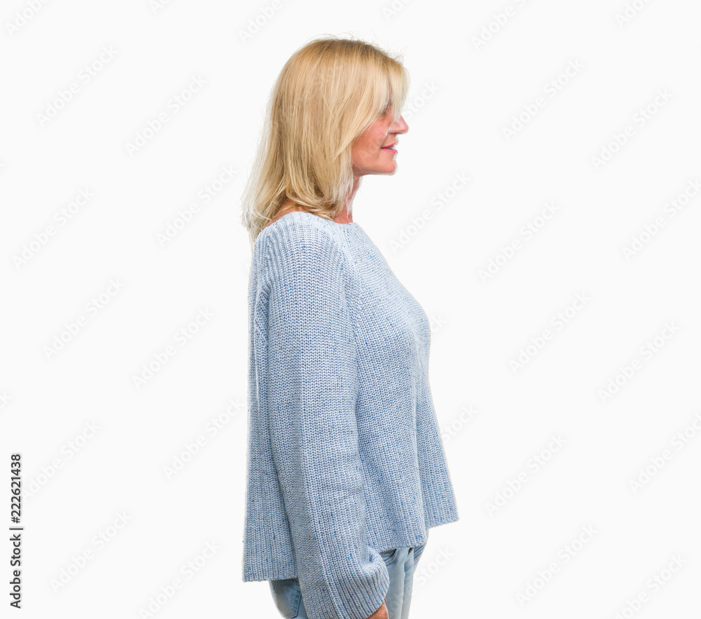 Middle age blonde woman wearing winter sweater over isolated background looking to side, relax profile pose with natural face with confident smile. Middle age blonde woman wearing winter sweater over isolated background looking to side, relax profile pose with natural face with confident smile.