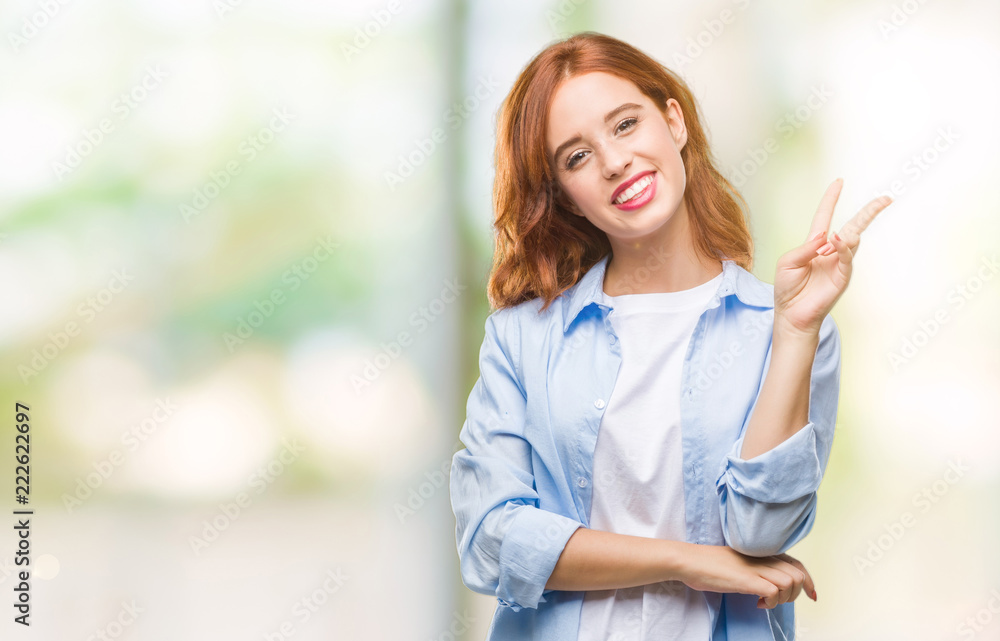 Fototapeta premium Young beautiful business woman over isolated background smiling with happy face winking at the camera doing victory sign. Number two.