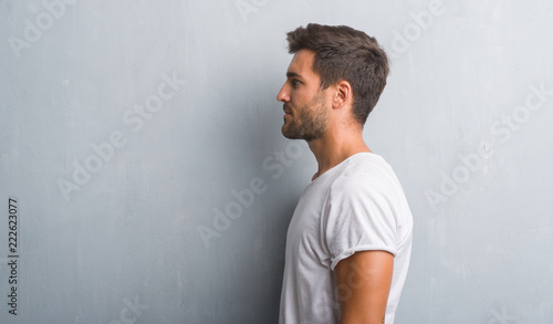 Vászonkép Handsome young man over grey grunge wall looking to side, relax profile pose with natural face with confident smile