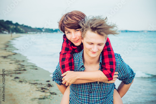 Portrait of woman carrying on happy young man's back. Couple enjoying each other, having fun on the beach. Date and love story concept. Lovers happy moments on holiday. Selective focus, copy space.