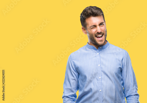 Young handsome man over isolated background winking looking at the camera with sexy expression, cheerful and happy face.