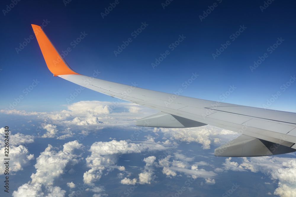 Wing of a flying airplane in a blue sky Wing of a flying airplane in a blue sky