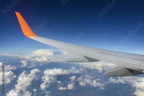 Wing of a flying airplane in a blue sky