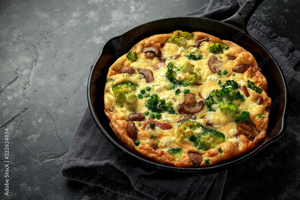 Homemade Frittata with mushrooms, broccoli, feta cheese, green peas and bacon on cast iron skillet Homemade Frittata with mushrooms, broccoli, feta cheese, green peas and bacon on cast iron skillet