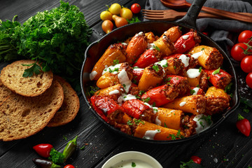 Sausage meat, mince and rice Stuffed sweet mini bell peppers baked in cast iron skillet, pan topped with yogurt and fresh parsley
