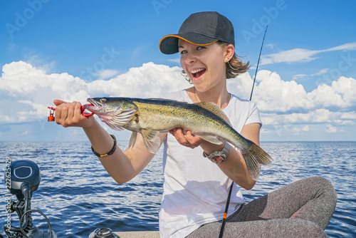 Happy fisher girl with walleye zander fish trophy at the boat