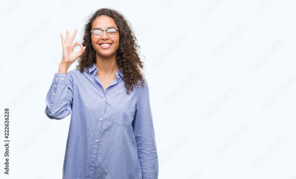 Beautiful young hispanic woman wearing glasses doing ok sign with fingers, excellent symbol Beautiful young hispanic woman wearing glasses doing ok sign with fingers, excellent symbol