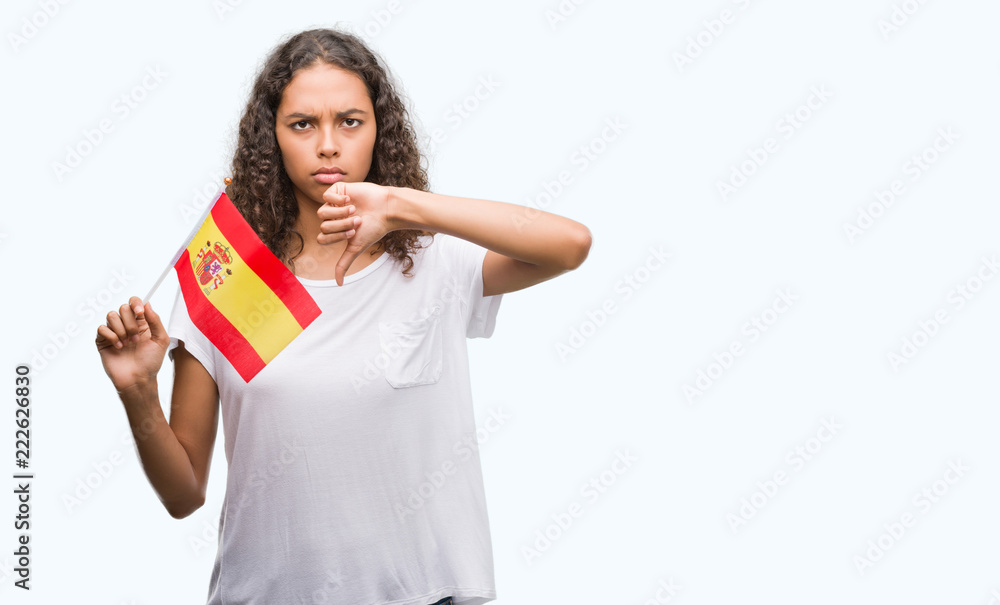 Young hispanic woman holding flag of Spain with angry face, negative sign showing dislike with thumbs down, rejection concept Young hispanic woman holding flag of Spain with angry face, negative sign showing dislike with thumbs down, rejection concept