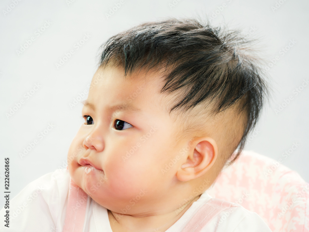 Portrait of cute short hair asia baby girl frowned and look something on white background Portrait of cute short hair asia baby girl frowned and look something on white background