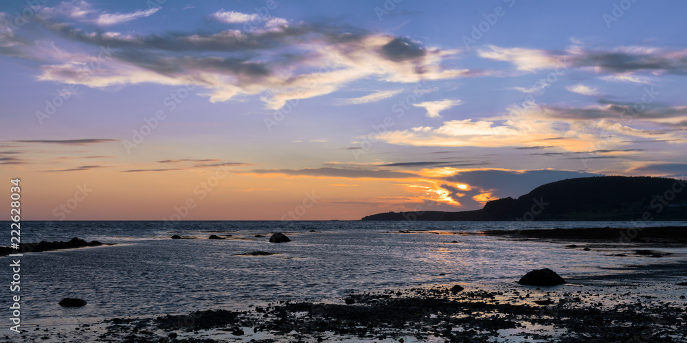 Sunset over Rocky Harbour in Newfoundland with the Lobster Cove Lighthouse in the distant background
