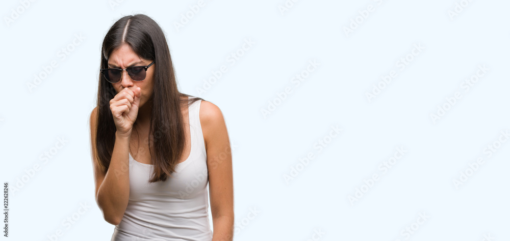 Young beautiful hispanic wearing sunglasses feeling unwell and coughing as symptom for cold or bronchitis. Healthcare concept. Young beautiful hispanic wearing sunglasses feeling unwell and coughing as symptom for cold or bronchitis. Healthcare concept.