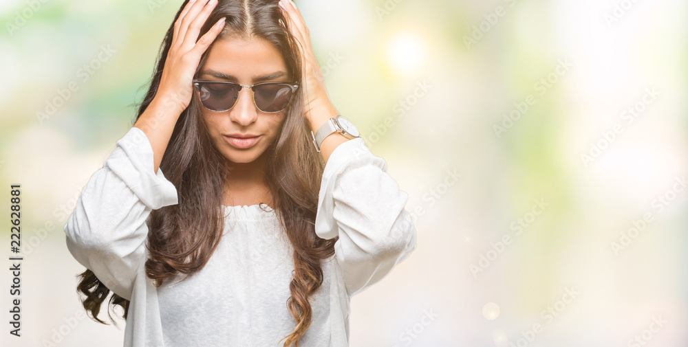 Fototapeta premium Young beautiful arab woman wearing sunglasses over isolated background suffering from headache desperate and stressed because pain and migraine. Hands on head.