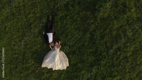 Top view of wedding couple lying on green grass and resting