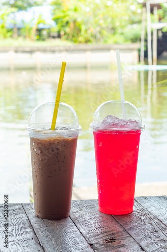 Iced coffee, iced tea and red soda on the table by the river.