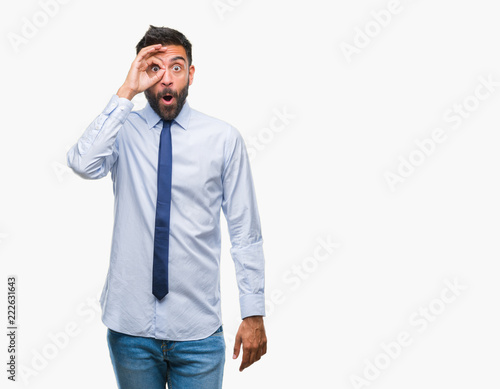 Adult hispanic business man over isolated background doing ok gesture shocked with surprised face, eye looking through fingers. Unbelieving expression.