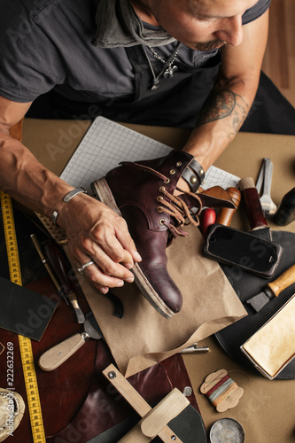 Shoe or belt maker working place at leather workshop with cobbler s and craft tools on background