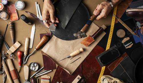 Foto Close up of leather designer hands making custom made shoes working with genuine leather and hammer at a workshop