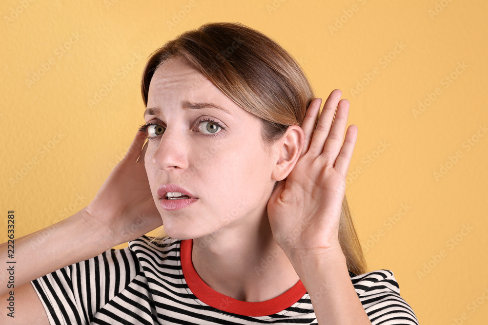 Young woman with hearing problem on color background Young woman with hearing problem on color background