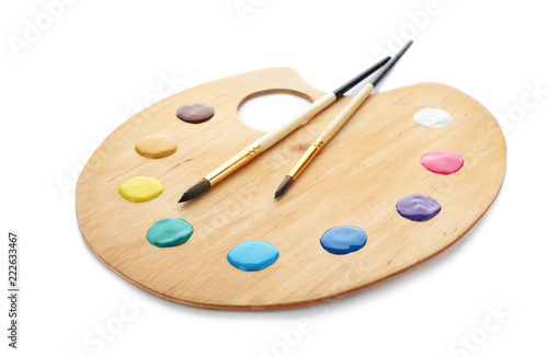 Palette with paints and brushes on white background