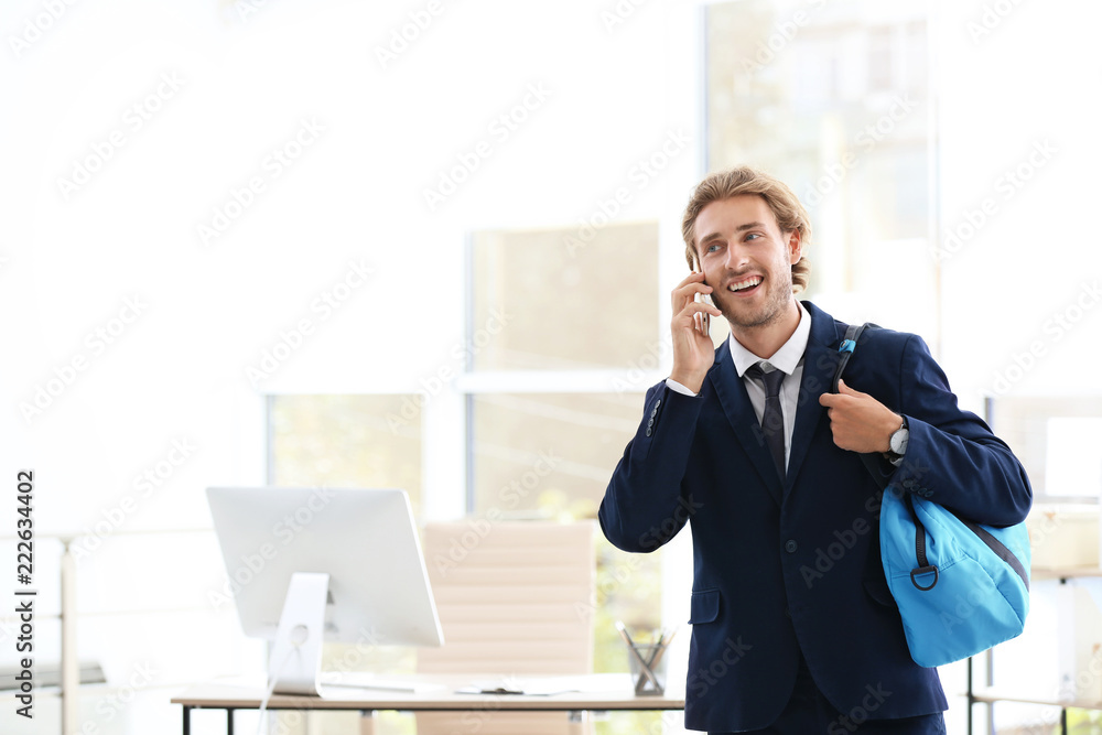 Young handsome businessman holding fitness bag in office. Space for text Young handsome businessman holding fitness bag in office. Space for text