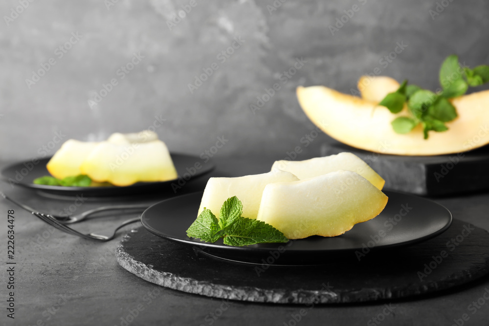 Slices of fresh ripe melon on table against gray background Slices of fresh ripe melon on table against gray background