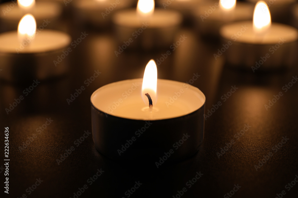 Burning candle on table in darkness, closeup. Funeral symbol Burning candle on table in darkness, closeup. Funeral symbol
