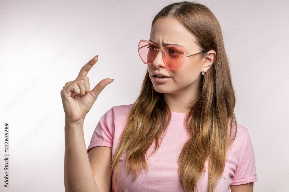 surprised girl looking at her two fingers. close up side view photo. fashion girl with crooked fingers. close-up studio shot. surprised girl looking at her two fingers. close up side view photo. fashion girl with crooked fingers. close-up studio shot.
