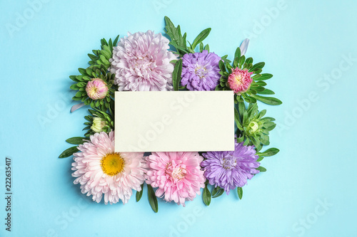 Beautiful aster flowers with sheet of paper on color background  top view. Space for text