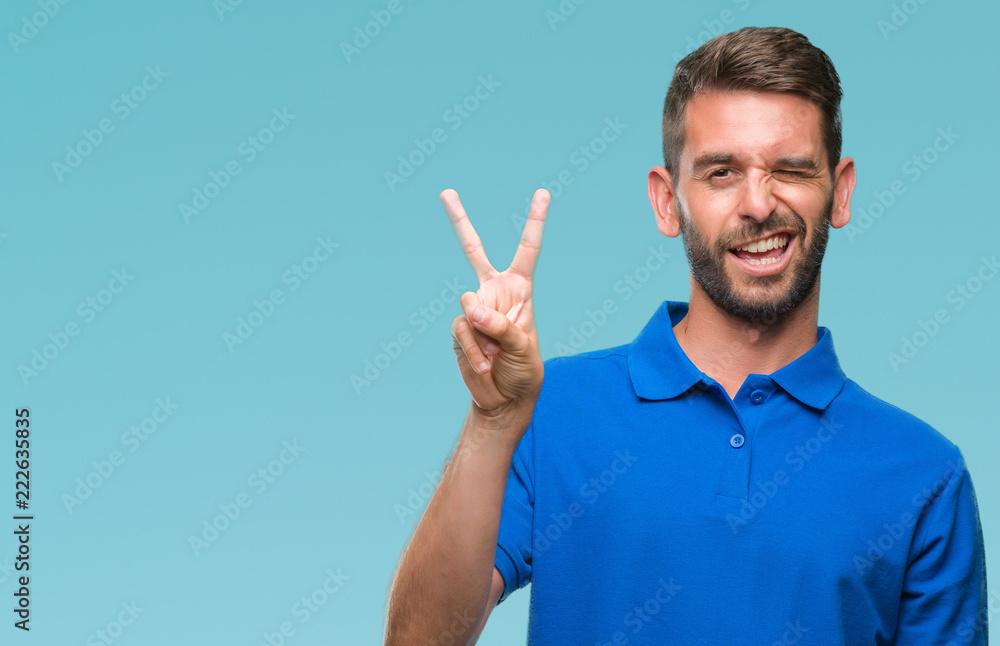 Young handsome man over isolated background smiling with happy face winking at the camera doing victory sign. Number two. Young handsome man over isolated background smiling with happy face winking at the camera doing victory sign. Number two.