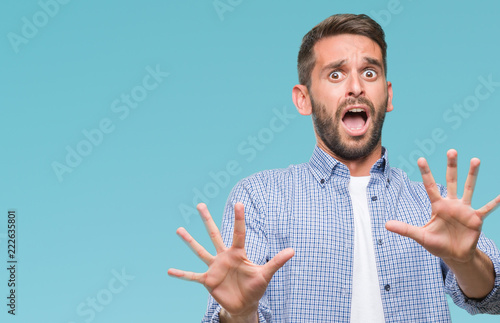 Young handsome man wearing white t-shirt over isolated background afraid and terrified with fear expression stop gesture with hands, shouting in shock Fototapet