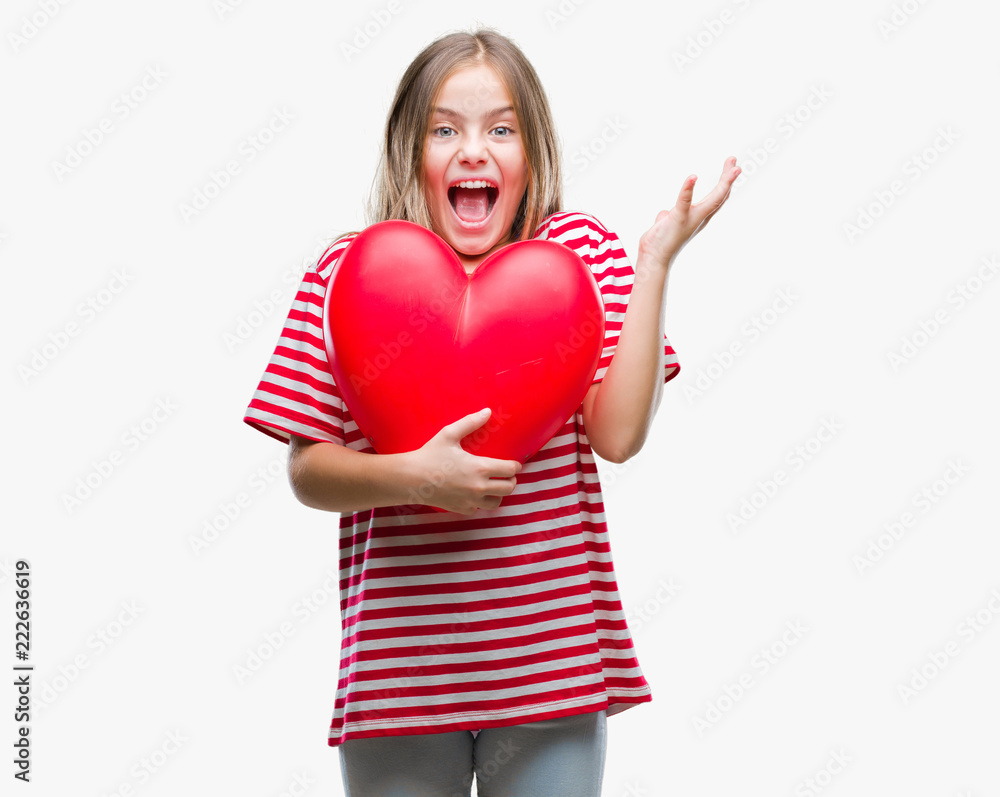 Young beautiful girl holding red heart over isolated background very happy and excited, winner expression celebrating victory screaming with big smile and raised hands Young beautiful girl holding red heart over isolated background very happy and excited, winner expression celebrating victory screaming with big smile and raised hands