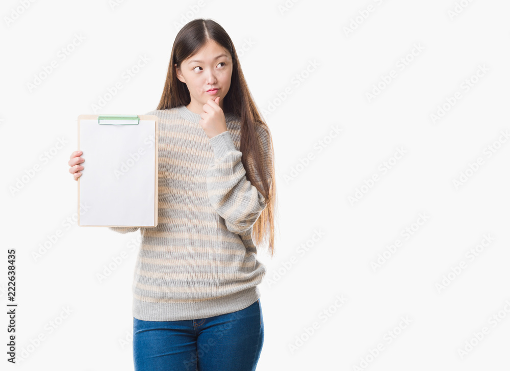 Young Chinese woman over isolated background holding clipboard serious face thinking about question, very confused idea Young Chinese woman over isolated background holding clipboard serious face thinking about question, very confused idea