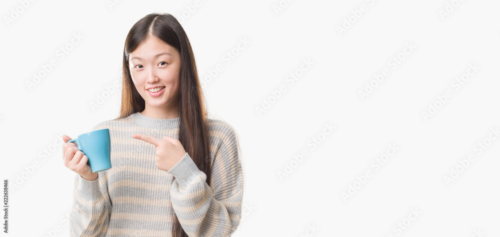 Young Chinese woman over isolated background driking cup of coffee very happy pointing with hand and finger Young Chinese woman over isolated background driking cup of coffee very happy pointing with hand and finger