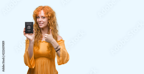 Young redhead woman holding passport of United States of America happy with big smile doing ok sign, thumb up with fingers, excellent sign