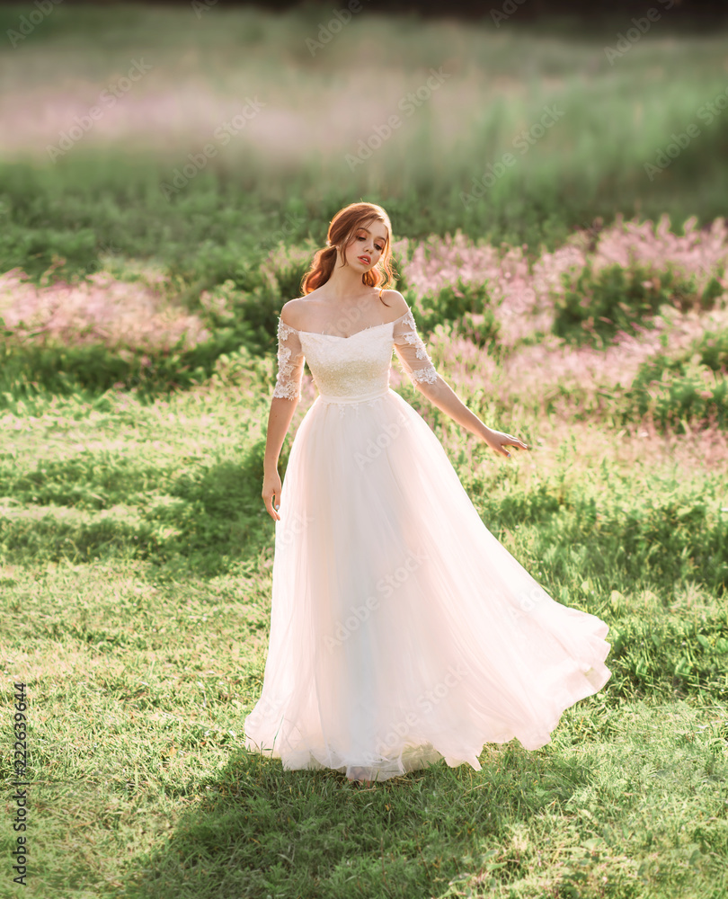 a kind fairy in a white dress is dancing in a clearing of beautiful pink flowers. graceful princess. freedom and happiness. nice girl wearing light clothes. art photo, wedding, bride. open shoulders.