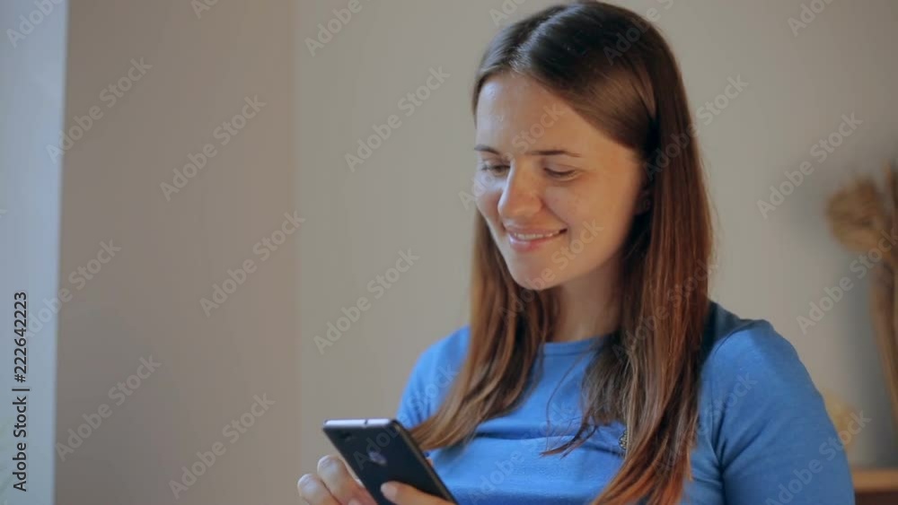 Pregnant woman texting on a mobile on line phone sitting on a sofa in the living room at home. Pregnant woman texting on a mobile on line phone sitting on a sofa in the living room at home.