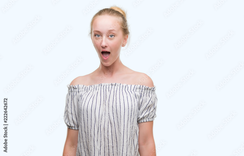 Blonde teenager woman wearing a bun scared in shock with a surprise face, afraid and excited with fear expression Blonde teenager woman wearing a bun scared in shock with a surprise face, afraid and excited with fear expression