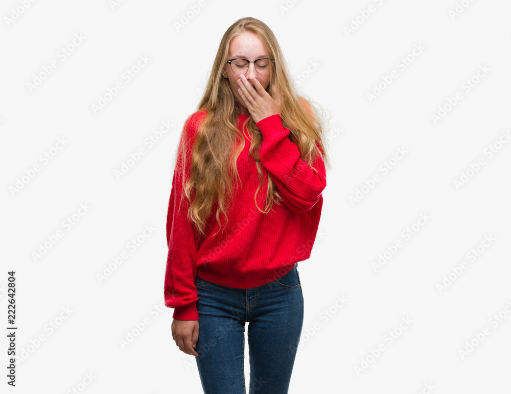 Blonde teenager woman wearing red sweater bored yawning tired covering mouth with hand. Restless and sleepiness. Blonde teenager woman wearing red sweater bored yawning tired covering mouth with hand. Restless and sleepiness.