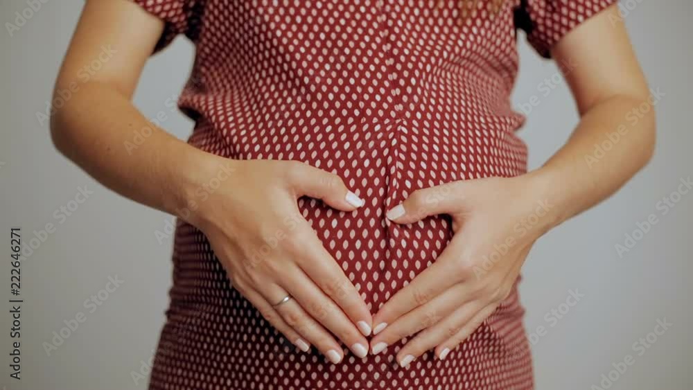 Pregnant belly, hugging the stomach and hands in the shape of the heart. Pregnant belly, hugging the stomach and hands in the shape of the heart.