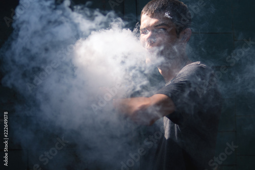 Male vaper on a dark background closeup cloud of steam