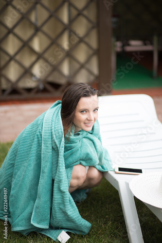 Smiling young awesome woman wrapped in bath towel sfter swimming near the lounge. close up photo. photo