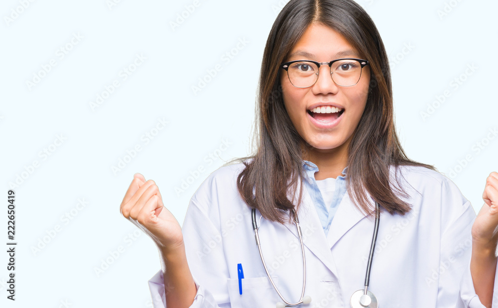 Young asian doctor woman over isolated background celebrating surprised and amazed for success with arms raised and open eyes. Winner concept.