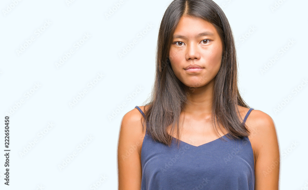 Young asian woman over isolated background with serious expression on face. Simple and natural looking at the camera. Young asian woman over isolated background with serious expression on face. Simple and natural looking at the camera.