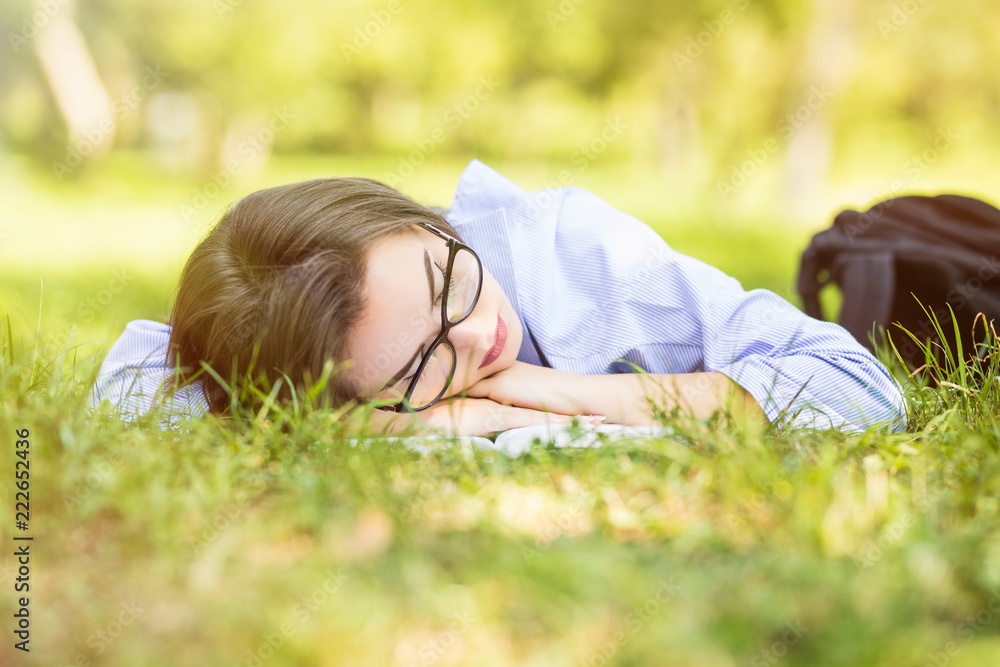 Beautiful young woman fall sleeping on fresh grass in park Beautiful young woman fall sleeping on fresh grass in park