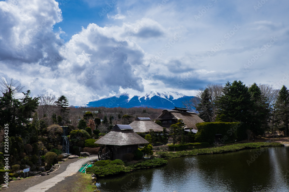 The view of an ancient village Oshino Hakkai at the foot of Mount Fuji - Fujiyama, with pond in the background and Fuji covered with clouds in the background