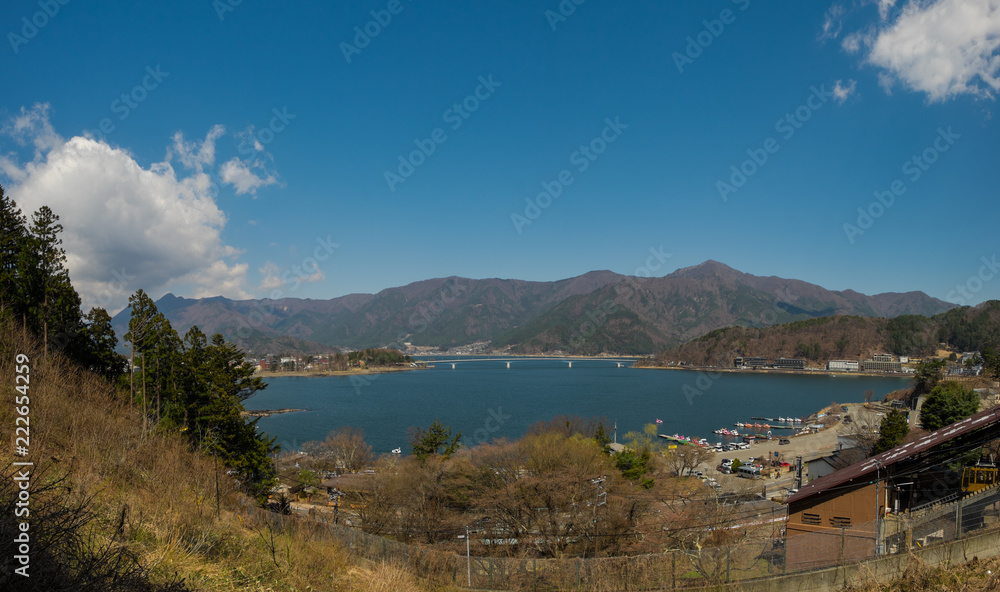 View from above of Kawaguchi lake located near Fuji mountain and surrounded by mountains, with buildings and hotels on the shore